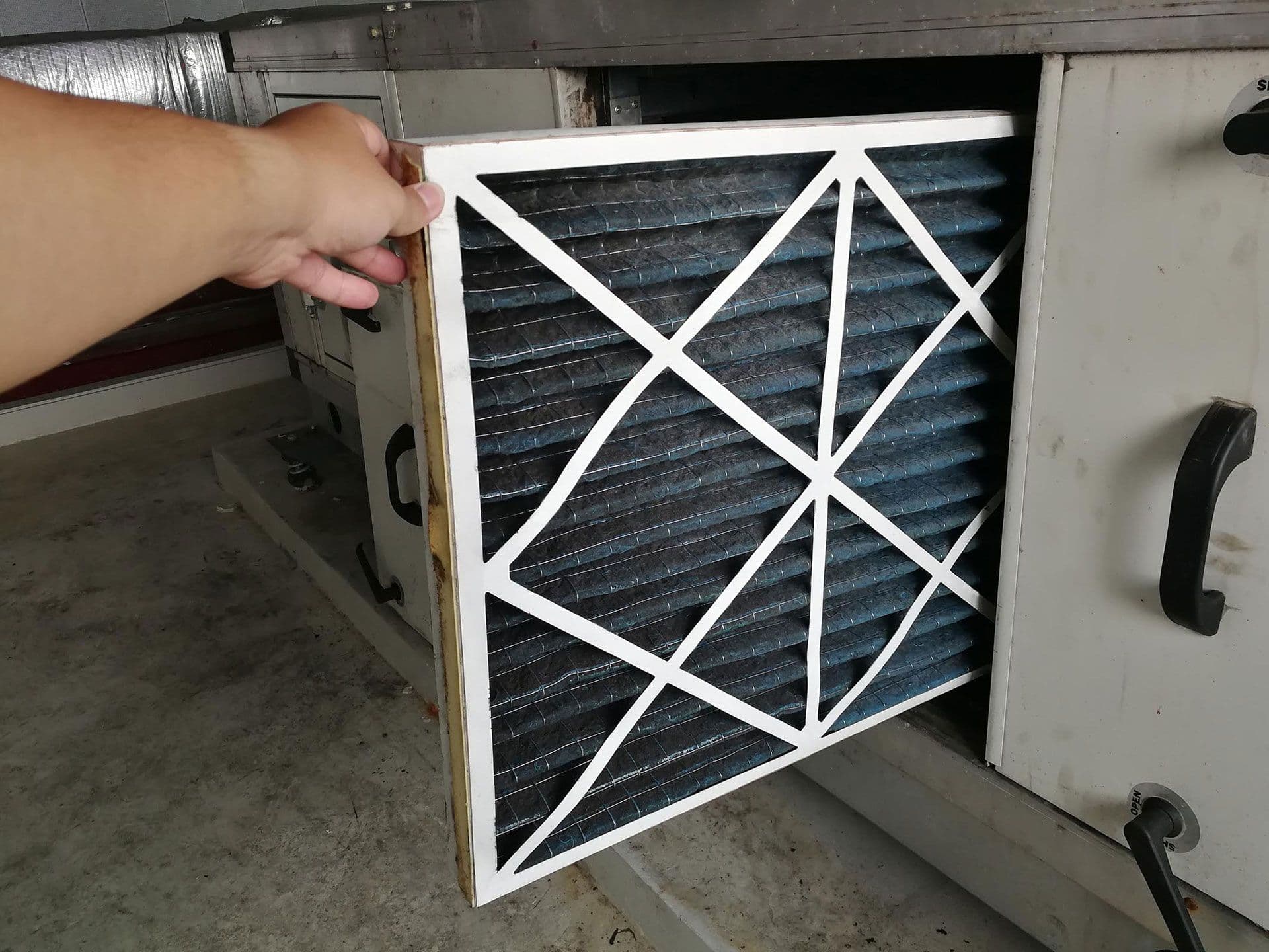 A person pulls an air filter from an HVAC system.