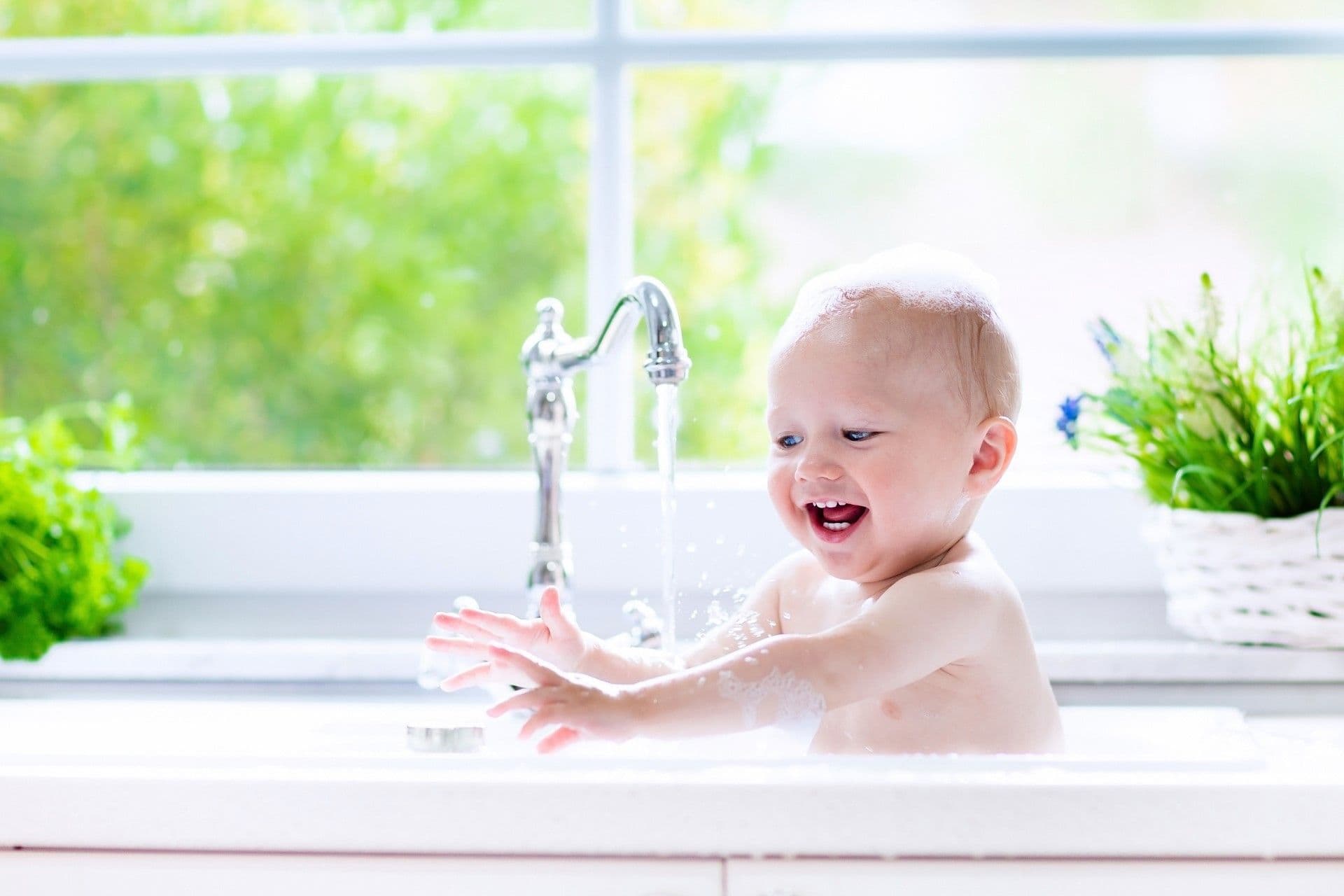 Baby taking a bath in kitchen sink